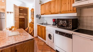 Une cuisine compacte dotée de meubles en bois, d’un four à micro-ondes, d’une machine à café et d’un lave-linge.