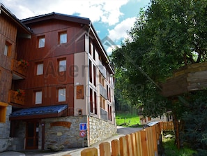 A multi-story building with a stone facade, wooden balconies, and a sign indicating a restaurant.