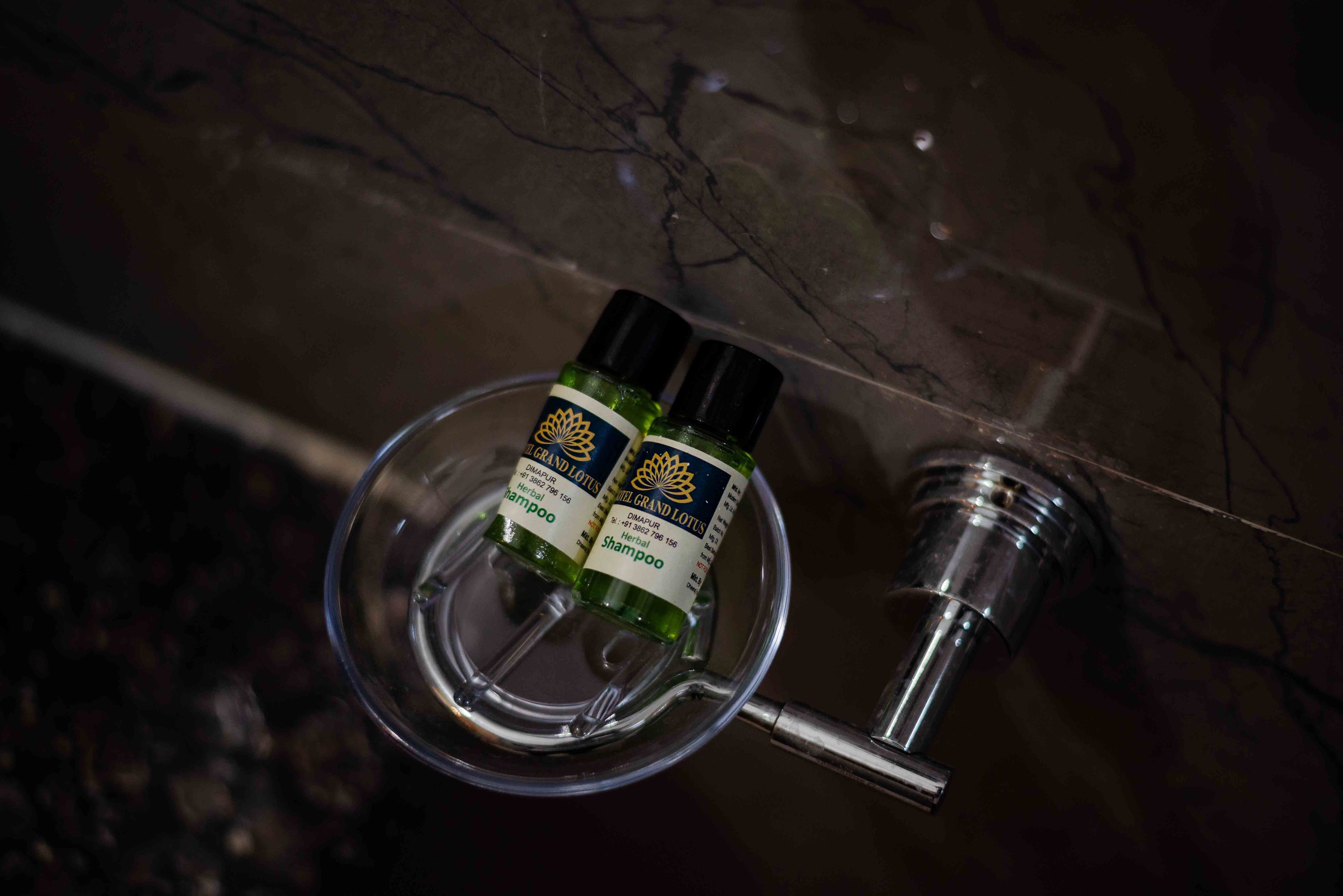 Two bottles of Grand Lotus shampoo on a marble surface.