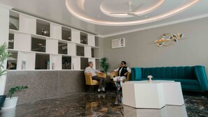 A modern lobby with a teal sofa, a white coffee table, and a ceiling fan. - Grand Lotus Dimapur (Dimapur)