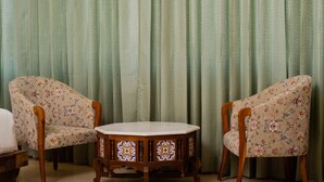 A room with two floral-patterned armchairs and a small wooden table with a white top. - Grand Lotus Dimapur (Dimapur)