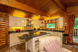 A cozy cabin-style kitchen with wooden beams, a central island, and a window overlooking greenery.