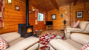 A cozy log cabin interior with a fireplace, leather sofas, and a television. - Luxury log cabin with veranda nestled in Kenwick Park, Louth (Louth)