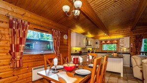 A wooden cabin interior with a dining area, kitchen, and a cozy living space. - Luxury log cabin with veranda nestled in Kenwick Park, Louth (Louth)