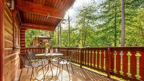 A wooden deck with a table and chairs, surrounded by a wooden fence and trees. - Luxury log cabin with veranda nestled in Kenwick Park, Louth (Louth)