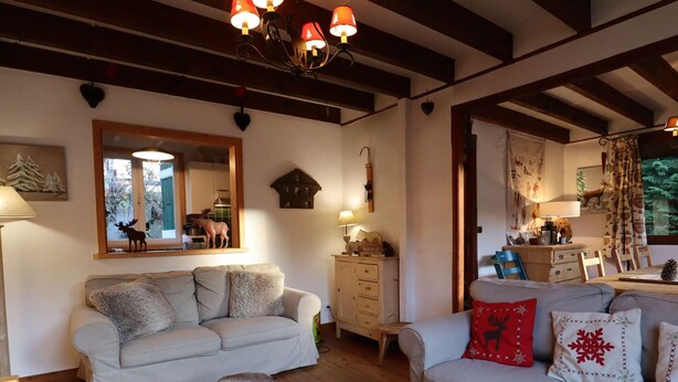 A cozy living room with two sofas, a wooden coffee table, a dresser, and a mirror reflecting a window view. - Chalet for 14 with terrace in the heart of Arêches-Beaufort (Arêches-Beaufort)