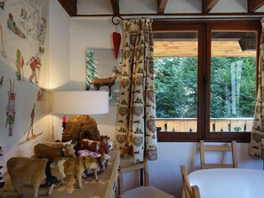 Um quarto aconchegante com teto de madeira, uma cama, uma escrivaninha com abajur e uma janela com cortinas.