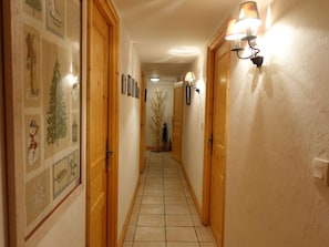 Un couloir étroit avec des portes en bois et un sol carrelé.