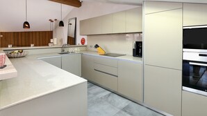 Una cocina moderna con horno integrado, cafetera y lavamanos.