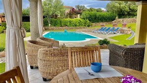 A covered patio area with wicker furniture, a pool, and a view of the surrounding garden. - Villa with private pool, 10 minutes from the sea, large garden*parking*BBQ  (Sardegna)