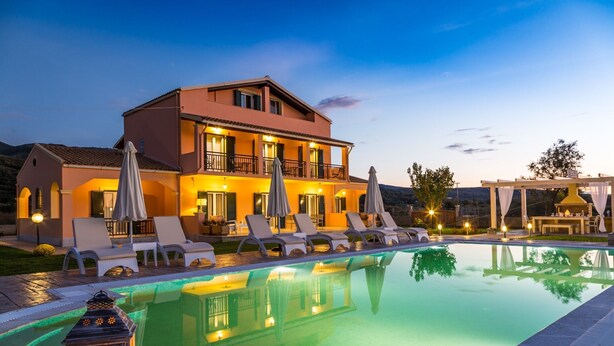 A two-story building with a swimming pool, lounge chairs, and umbrellas. - Eleni Luxury Villa by White Dream Villas (Corfu)
