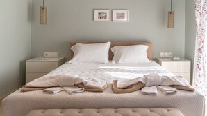 A neatly made bed with white linens and a beige ottoman in front. - Eleni Luxury Villa by White Dream Villas (Corfu)