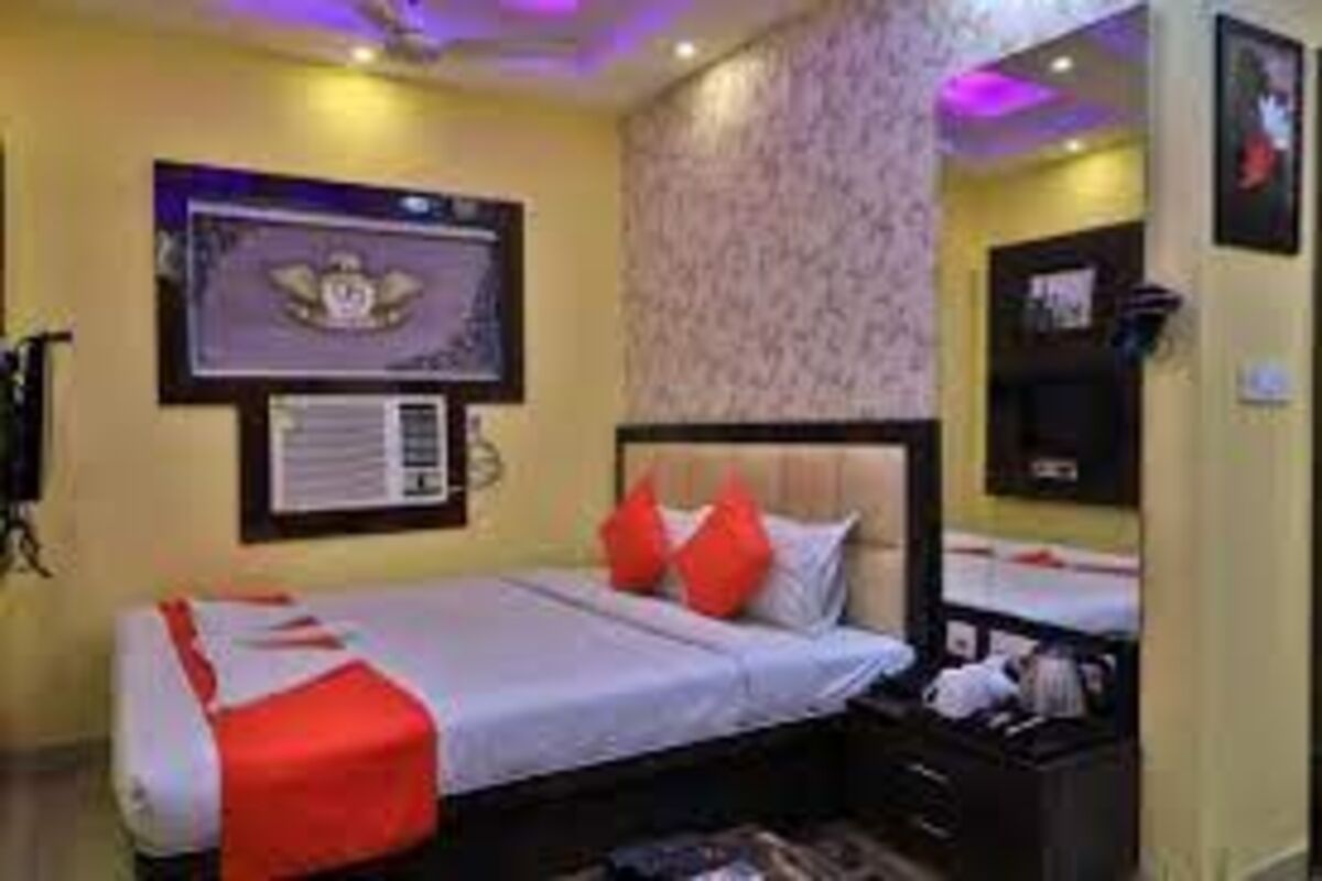 A hotel room with a bed, a nightstand, a wall-mounted TV, and a framed certificate on the wall.