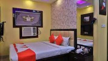 A hotel room with a bed, a nightstand, a wall-mounted TV, and a framed certificate on the wall.