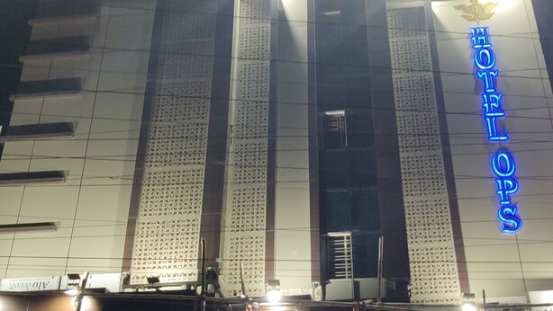 A hotel facade with a prominent neon sign reading "HOTEL OPS" and a decorative emblem above it. - Hotel OPS (Kolkata)