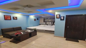 A modern hotel room with a sofa, a coffee table, and a bed. - Hotel OPS (Kolkata)