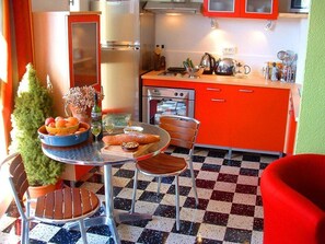 A kitchen with a red cabinet, a small potted plant, and a table with food items.