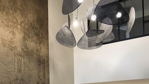 A modern interior with a large abstract painting, a dining area with a patterned chair, and a kitchen area with a refrigerator. - Domaine de Bonneuil (Bonneuil-les-Eaux)