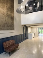Un interior moderno con un cuadro abstracto grande, una zona de comedor con una silla estampada y una cocina con refrigerador.