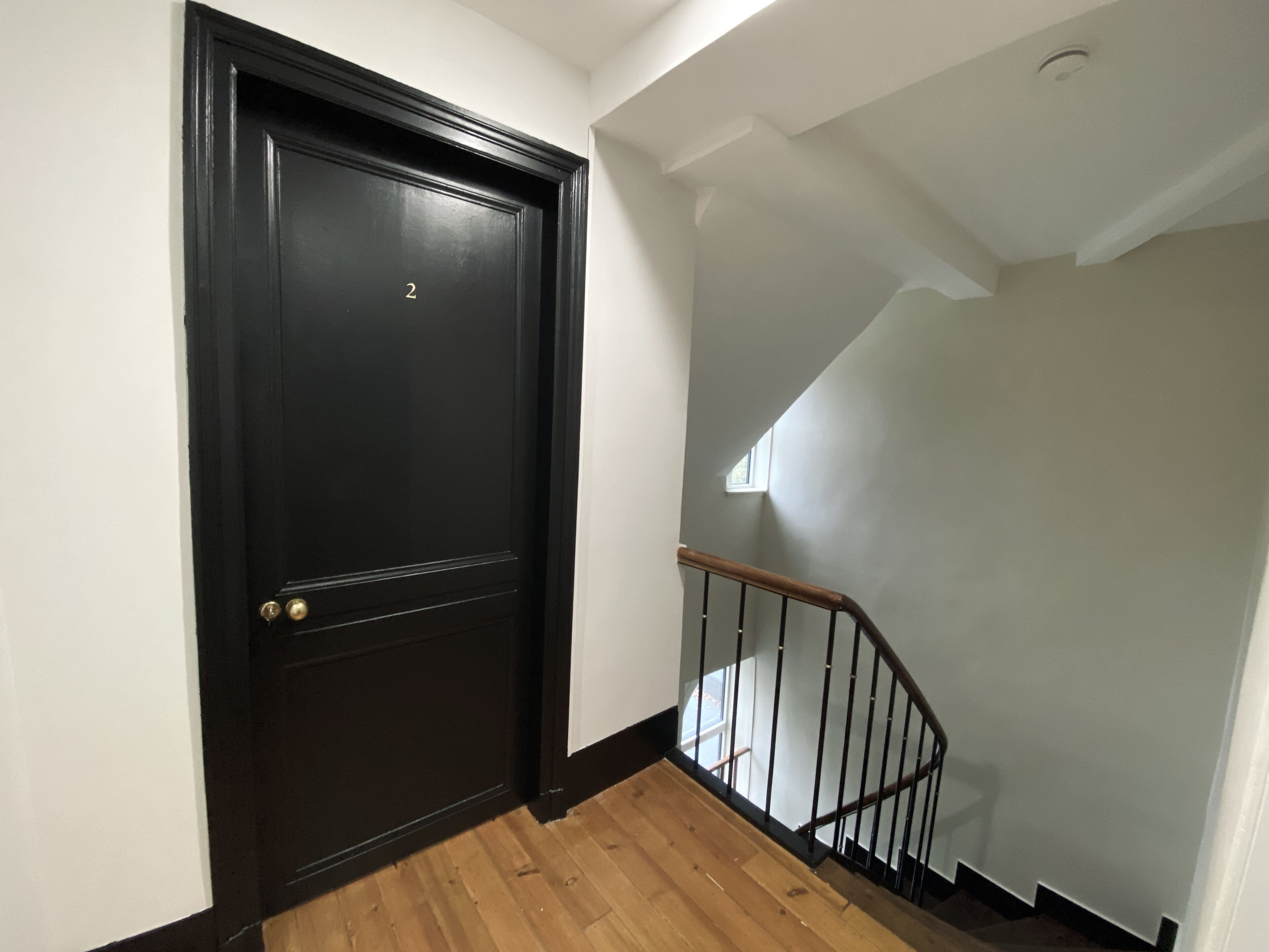 A black door with a brass doorknob and a small window above it.