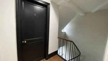 A black door with a brass doorknob and a small window above it.