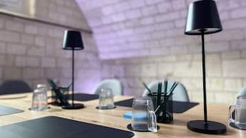 Un salón de conferencias con pared de ladrillo, dos lámparas de mesa negras y una taza de vidrio transparente sobre la mesa.