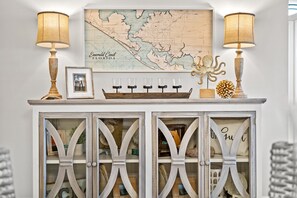 A white cabinet with glass doors, a map, and two lamps on top.