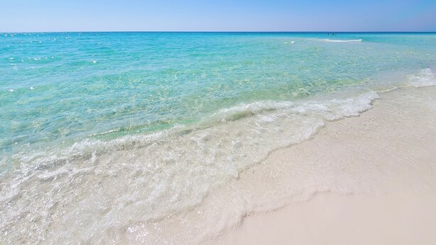 Ein Strand mit klarem türkisblauem Wasser und weißem Sand.