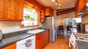 A kitchen with wooden cabinets, a stainless steel refrigerator, a sink, and a stove. - 🌲Your Home Base for Exploring the Redwoods! Pet Friendly, Complete with Hot Tub!🐾 (Mckinleyville)