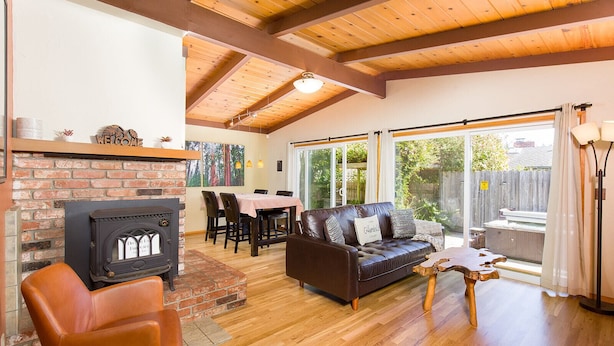 A cozy living room with a fireplace, a leather sofa, and a dining area. - 🌲Your Home Base for Exploring the Redwoods! Pet Friendly, Complete with Hot Tub!🐾 (Mckinleyville)