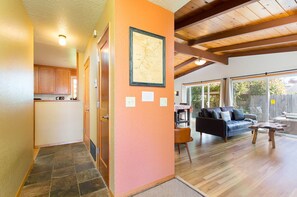 A spacious living area with a wooden ceiling, a black leather sofa, and a dining table.