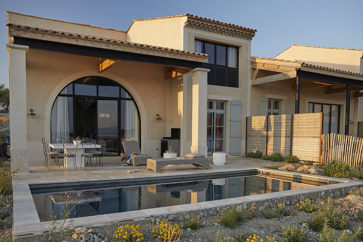 A modern house with a swimming pool, outdoor seating, and a large arched window.