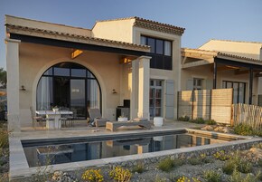 Uma casa moderna com piscina, área de estar externa e uma grande janela em arco.