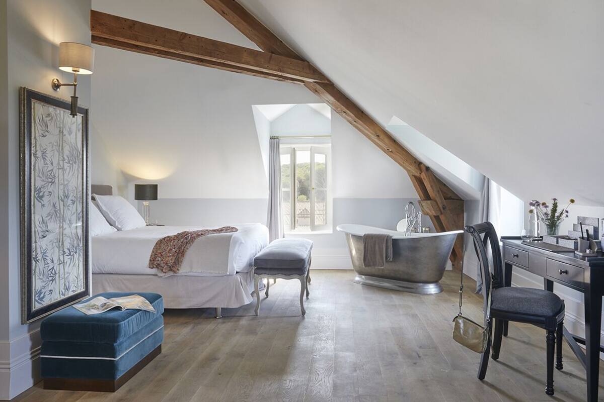 A bedroom with a large bed, a sitting area, a bathtub, and a desk.