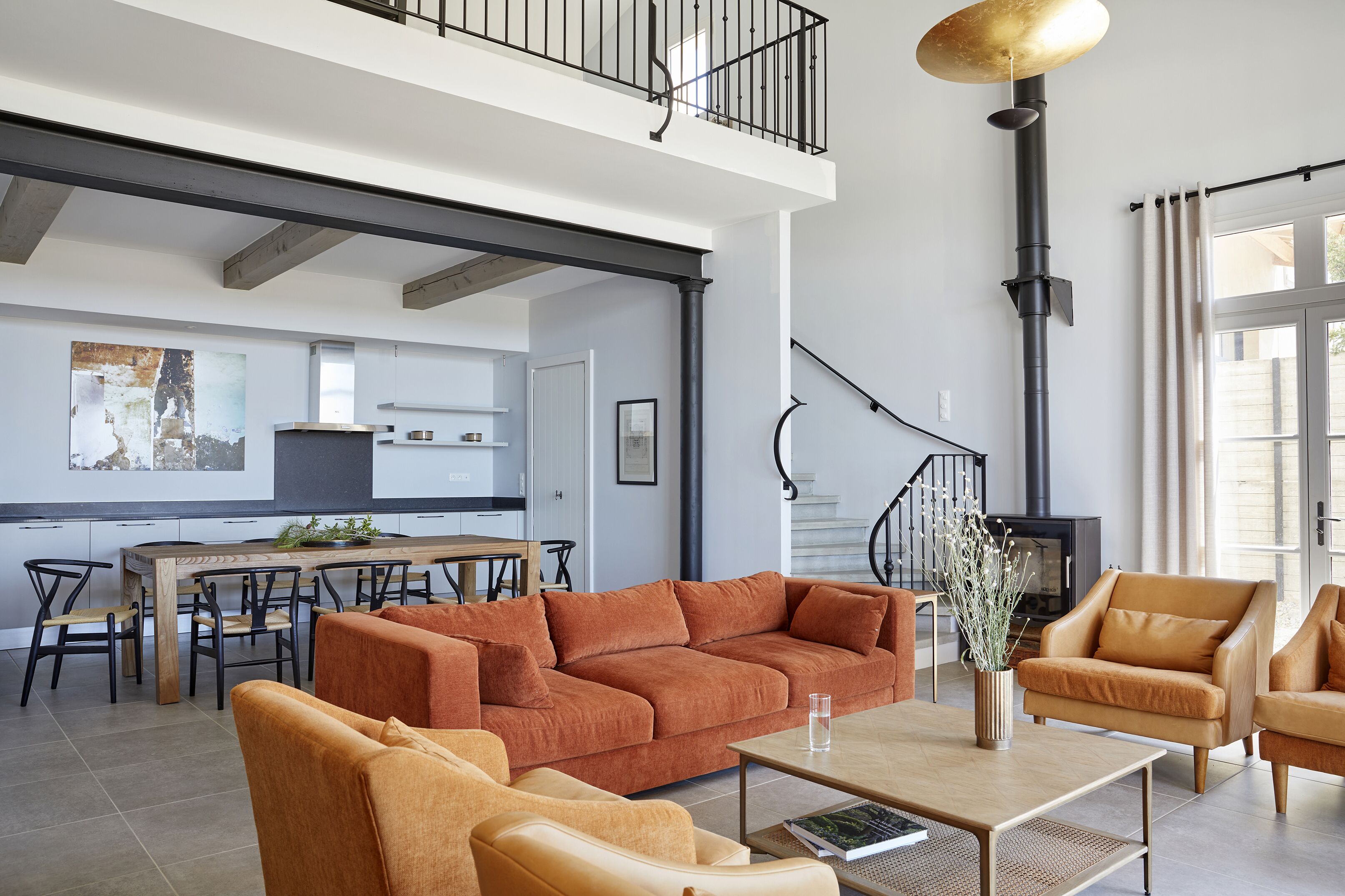 A spacious living area with a high ceiling, a dining table, and a sofa set.