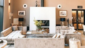A spacious living room with a fireplace, modern furniture, and a large circular light fixture. - Château Capitoul (Narbonne)