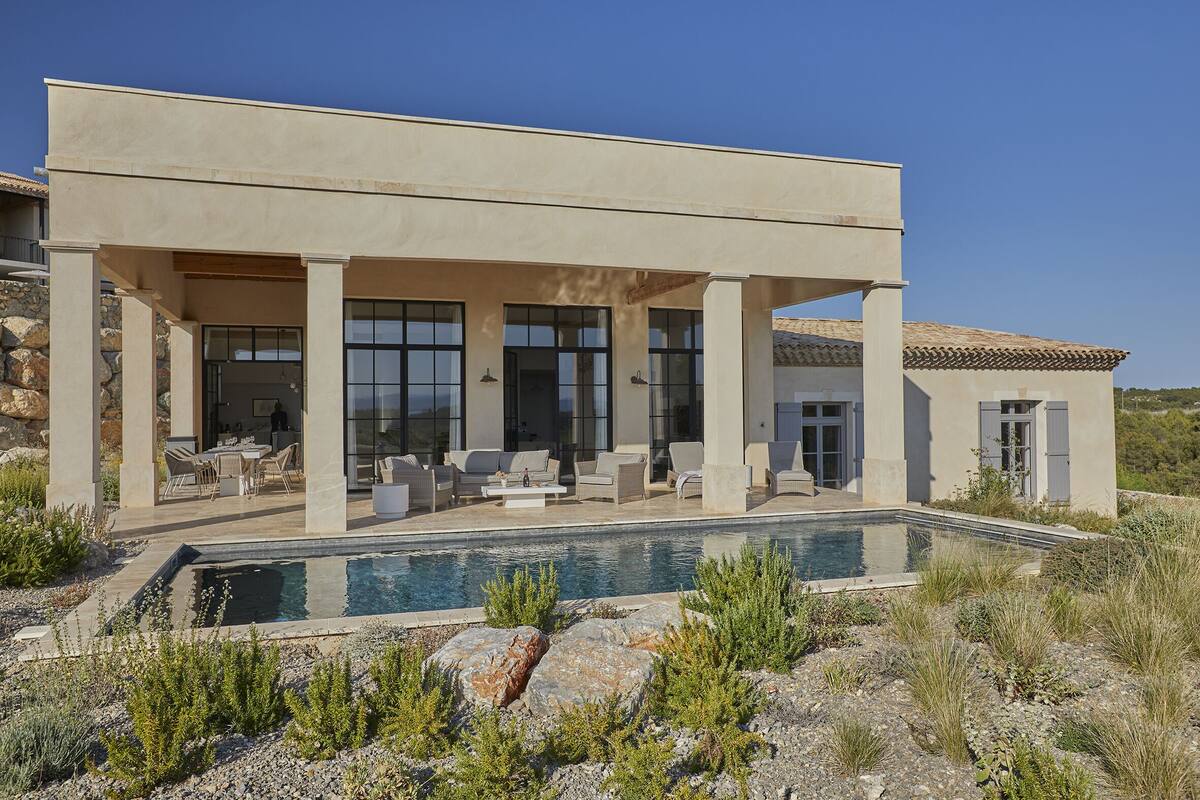 A modern house with a pool, outdoor seating, and a stone facade.