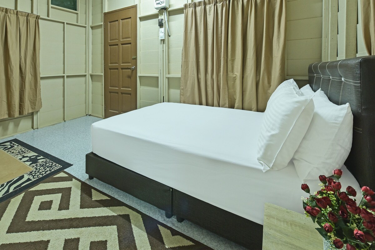 Een netjes ingerichte hotelkamer met een bed, een nachtkastje, een vaas met bloemen en een kamerbreed tapijt.