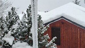 A wooden structure with icicles hanging from the roof, a snow-covered building in the background, and snow-laden trees. - Chalet La Plagne Tarentaise (LA PLAGNE MONTALBERT)