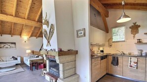 A rustic interior with a fireplace, wooden beams, a kitchen with wooden cabinets, and a dining area with a sofa and table. - Chalet La Plagne Tarentaise (LA PLAGNE MONTALBERT)