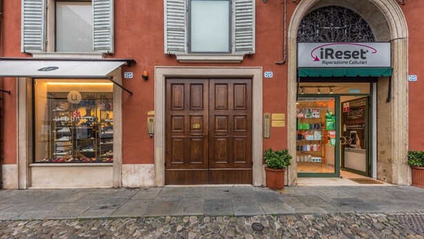 A storefront with a large wooden door and a sign for 'iReset Riparazione Cellari'. - L'Altana di Emilia Suite (Modena)