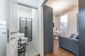 Relax in a spacious room with a glass-enclosed shower, sofa, and dining area.