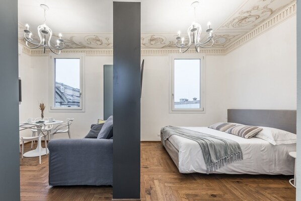 Relax in a spacious bedroom with a large bed, seating area, and city view.