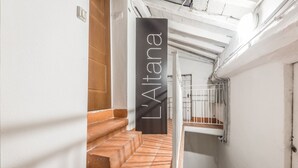 A narrow stairway with terracotta steps leading to a landing, a white wall, and a metal railing. - L'Altana di Emilia Suite (Modena)