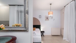 Un dormitorio con cama, mesita de noche, espejo, cómoda y ventana con cortinas.