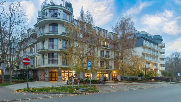 Un edificio residencial de varios pisos con balcones, un cartel de ‘prohibido el acceso’ y un cartel de estacionamiento.