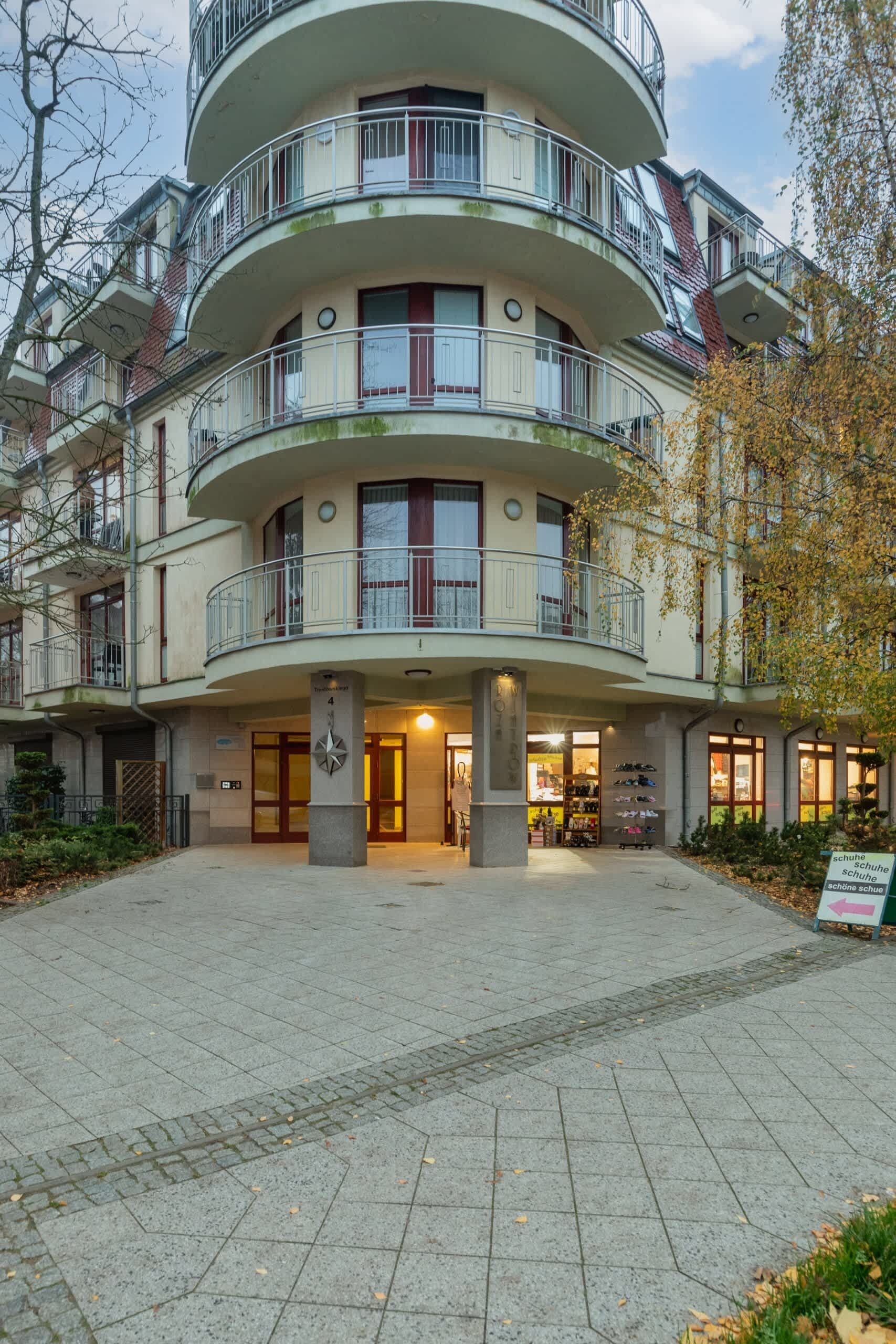 Ein mehrstöckiges Gebäude mit Innenhof, Balkonen und einem Schild, das auf ein Schuhgeschäft hinweist.