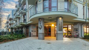 Un edificio de varios pisos con una entrada central, balcones y una zapatería en la planta baja.