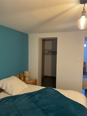 A bedroom with a bed, a bedside table with a lamp, and a closet.