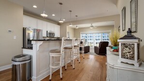 A modern kitchen with white cabinetry, stainless steel appliances, and a bar area with bar stools.